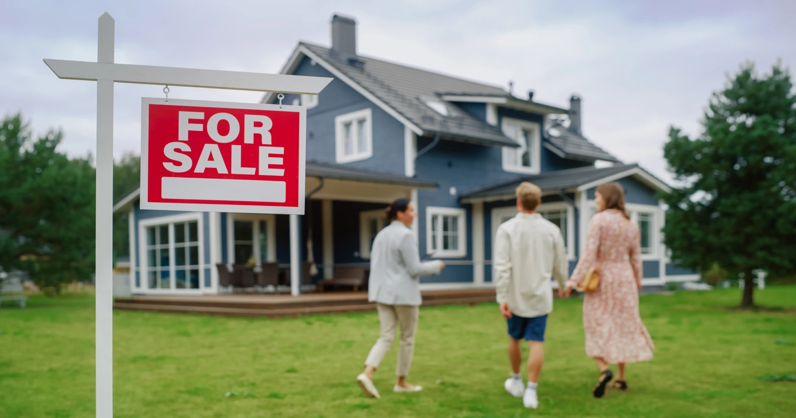 A buyer reviewing an REO property listing while standing outside a bank-owned home for sale at auction